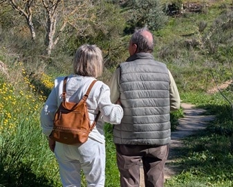 Dos personas mayores en una escapada a Río Frío, admirando la maravilla de la floración primaveral, rodeados de naturaleza